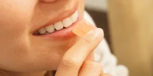 a woman about to put a colorful cannabis gummy in her mouth.