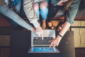 three females shopping online through their laptop.