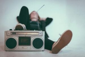 A young person listening to music through an old-school boombox.